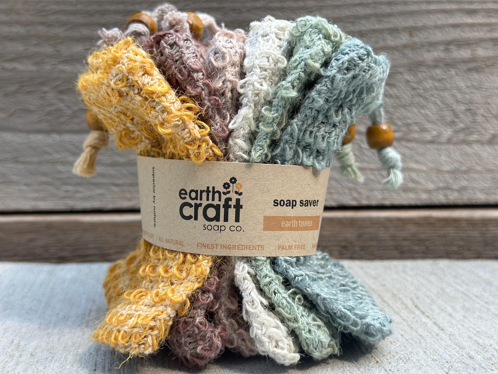 May include: A set of four earth tone soap savers. The savers are made of a soft, textured fabric and are designed to help extend the life of your soap bars. The savers are packaged with a label that reads 'earth craft soap co.' and 'soap saver earth tones'. The label also includes the text 'all natural', 'finest ingredients', and 'palm free'